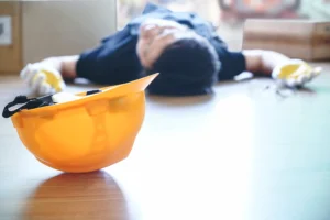 An injured worker with his hard hat on the floor.