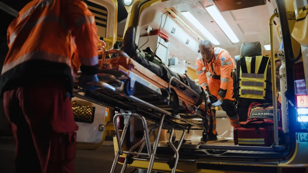 Emergency medical technicians bringing a gurney out of an ambulance.