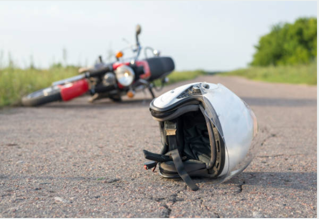 A motorcycle after a crash with a helmet in the road.