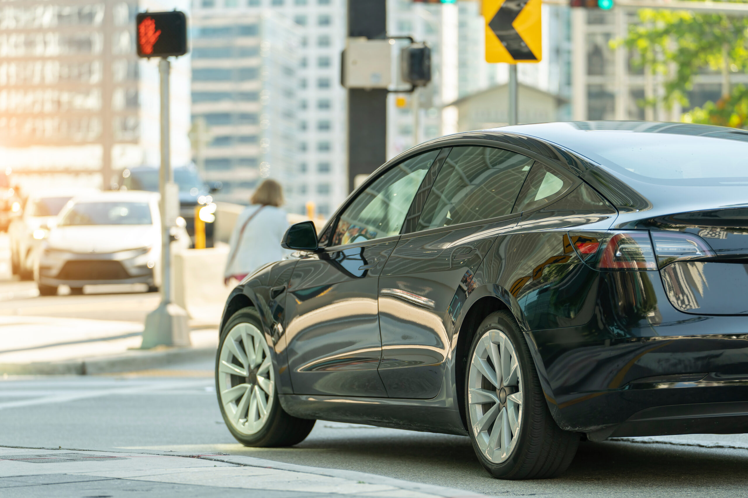 Electric car on Miami street. Traffic with driving cars at urban intersection with traffic lights in Florida