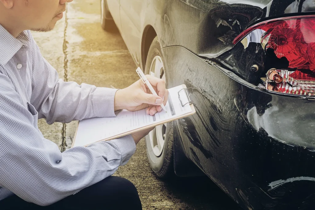 Insurance adjuster looking at a damaged car.