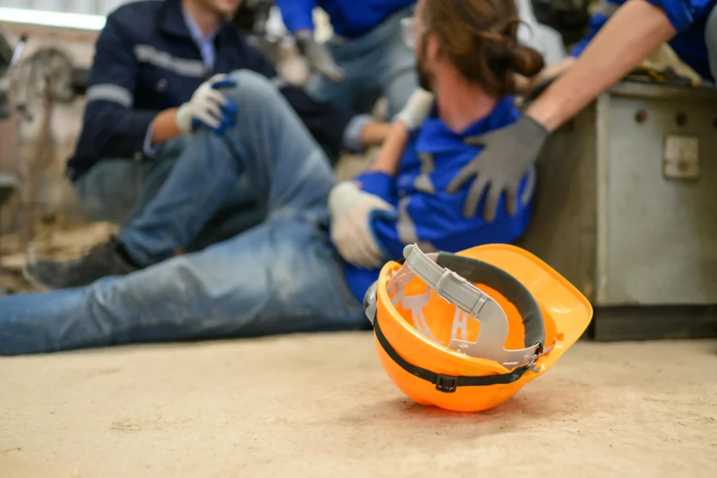 A worker getting injured with a hard hat on the ground.