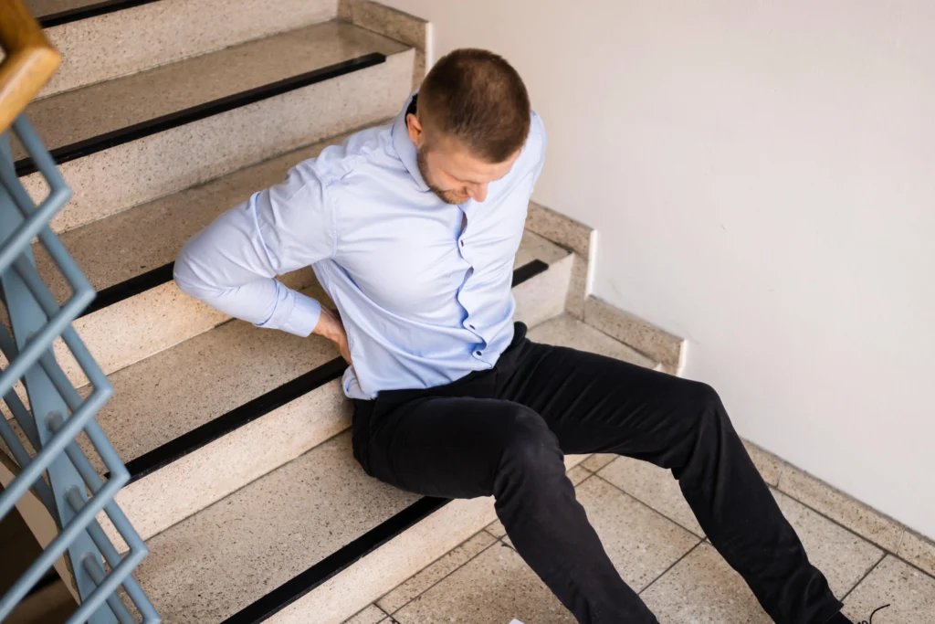 A man holding his back after falling down stairs.